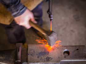 blacksmith striking hot metal on an anvil with sparks flying