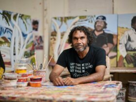 Vincent Namatjira in his studio in front of paintings