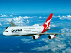 Qantas aircraft flying through blue sky and clouds
