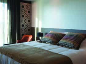 A king bed with white linen and colorful pillows