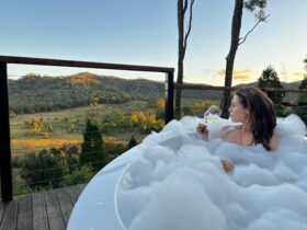 Lady soaking in an outdoor bath sipping on a glass of white wine