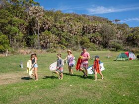A family walks from their tents to the beach, at The Ruins campground in Booti Booti National Park.