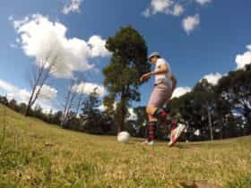 Man wearing golf clothing kicking soccerball