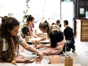 Picture shows a group of people on pottery wheels in a pottery studio