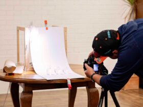 a person with a camera on a tripod taking a photo of 3 small vases on a white backdrop.