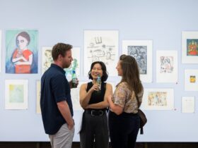 Three people having a conversation in front of artworks.