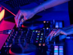 Hands operating a DJ turntable with a purple hue