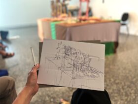 Sketch of art installation on a clipboard with a hand holding it
