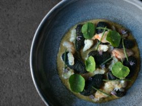 A dish of hand rolled squid ink gnocchi, crab, lobster bisque and garden nasturtiums