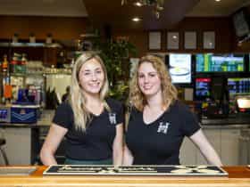 Two female staff members standing behind the bar