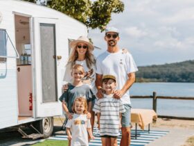 Family of four in front of vintage caravan with lake in the background