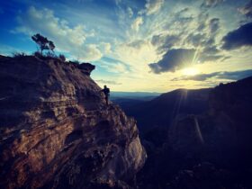 Climber traversing Mushroom Rock on rope at sunset