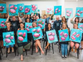 Happy group of people showing off their creations from a Paint and Sip evening.