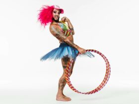 Circus performer dressed in bright clothing and tutu holding a hula hoop