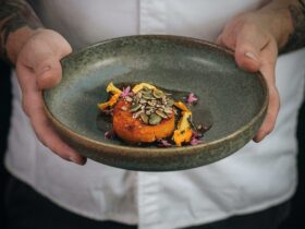 Alan holds a green plate with local roasted pumpkin, seed puree and flowers