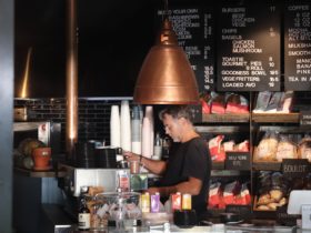 A Pantry barista is pictured making a coffee behind the counter, with shelves of bread behind him.