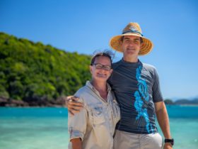 A caucasian womand and man are standing in front of a tropical island