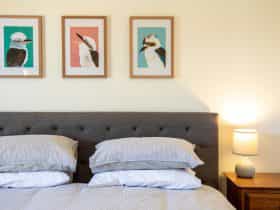 bed with three pictures of Kookaburras each with a coloured background and a lamp on a bedside table