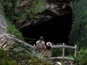 Two people looking standing behind railing, into the cave