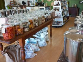Inside view of Nourish Home & Pantry. Dried fruit filled jars, bags of organic flour flour.