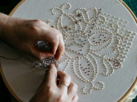 Sera Waters hands stitching a sampler pattern