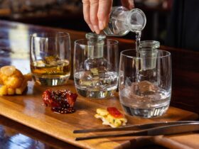Gin being poured into tasting glasses on a board with portions of matched food