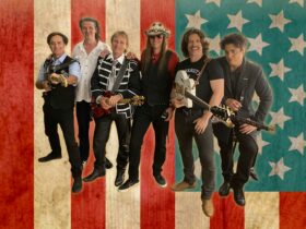 A group of country performers stand in front of the American flag