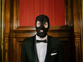 Image of a smartly dressed person in a tuxedo wearing a stocking balaclava