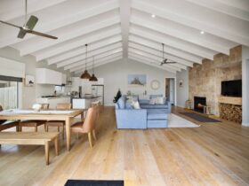 Large bright living space with exposed beams, modern kitchen, large comfortable couch & table, fans