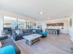 Image of large open plan living area with comfortable couches, timber floors, entertainers kitchen