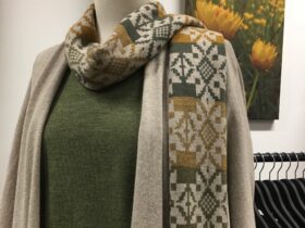 Mannequin wearing a woollen jumper, cardi and scarf in green, mushroom and mustard.