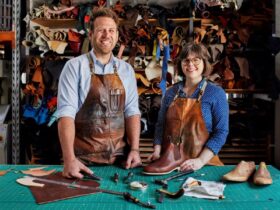 Jess and Krystina standing in front of leather storage with tools laid out on table in front