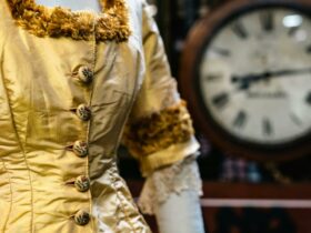 Close up of bust of gold 1850s dress with historical clock in background
