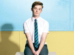 Person in school uniform sitting in front of blue and yellow wall.