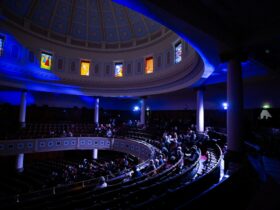 Image of a concert at Toorak Synagogue, Blue lighting, stained glass windows and a full house