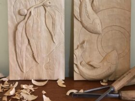 Two wooden carvings one featuring a gum leaf and koi fish