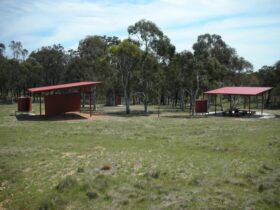 Two shelters, bathroom facility and trees in background
