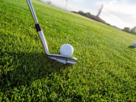 Golf club lining up shot on golf ball on green grass