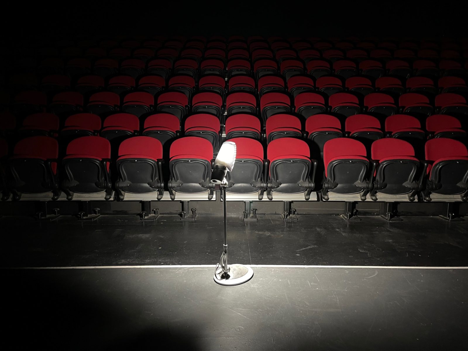 dimly lit image of light on a stand with red theatre seating in background