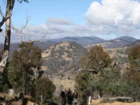 Three hikers on a trail looking at the views from Mt Tennent in Namadgi National Park