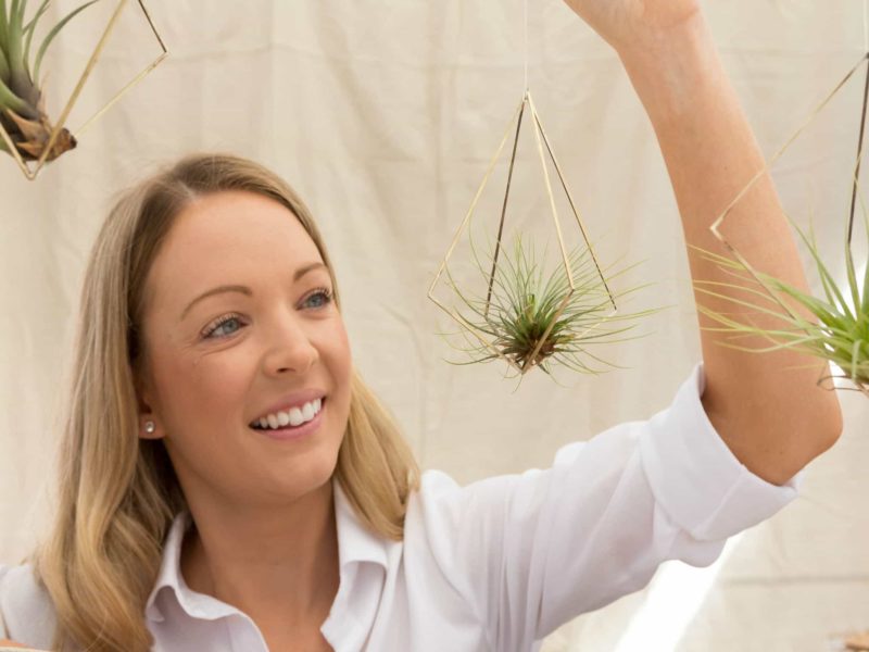 A visitor holding a hanging air plant at the Old Bus Depot Markets