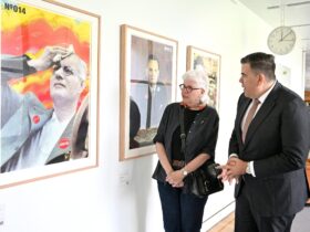 A man and woman looking at art work hanging on a wall and having a conversation.