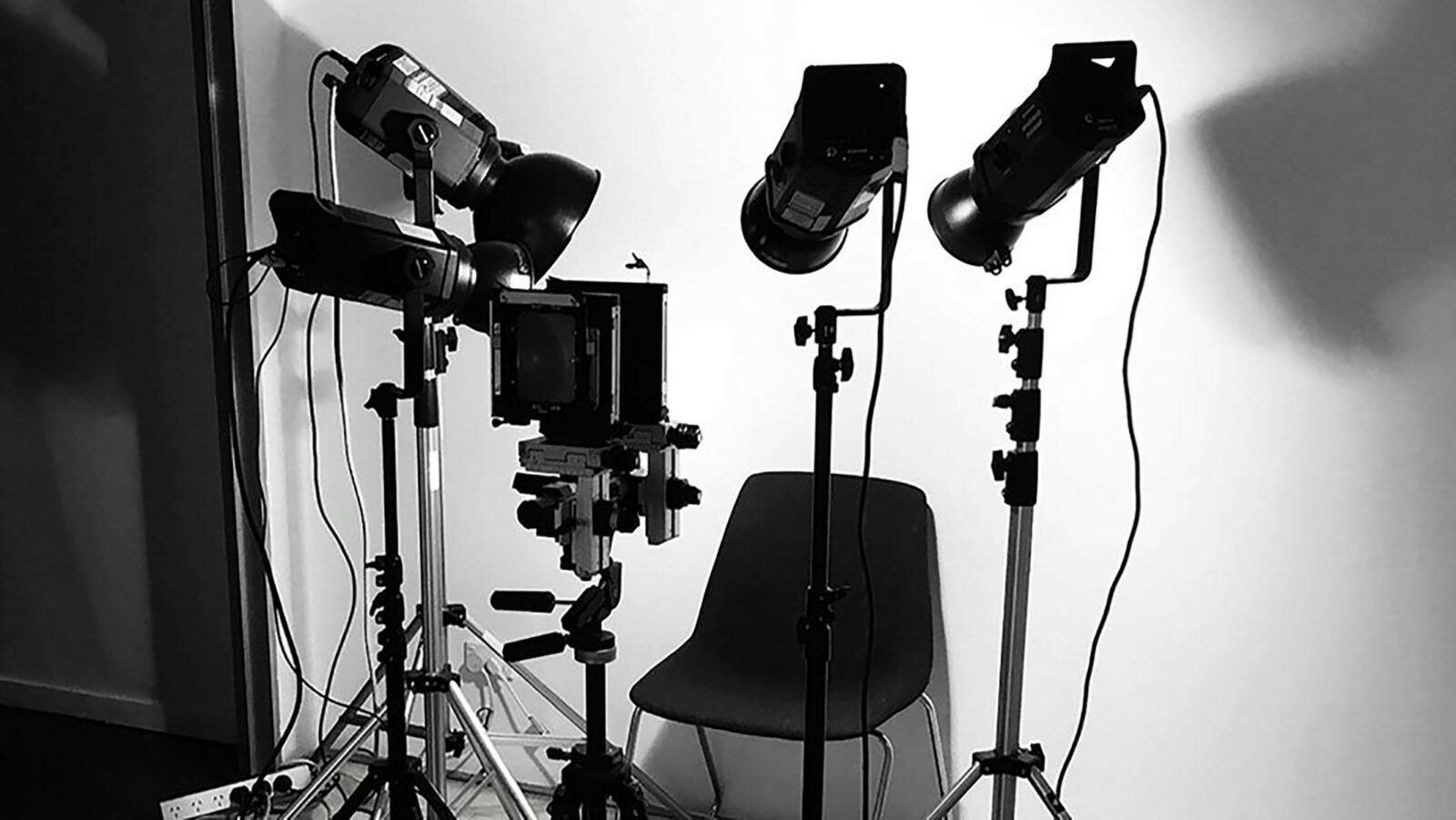 A photograph of a chair surrounded by studio lights and a camera