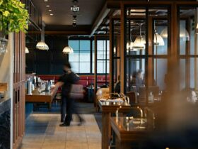 A busy restaurant with wood fixtures with a server walking through