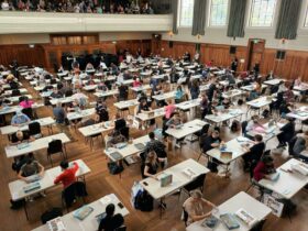 A large room with lots of people sitting at tables completing puzzles