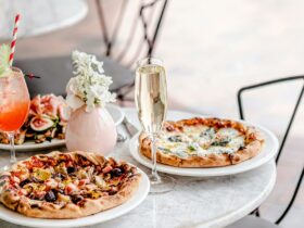 Glass of sparkling wine and pizza on a white topped table