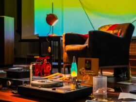An armchair in front of a turntable and a lava lamp