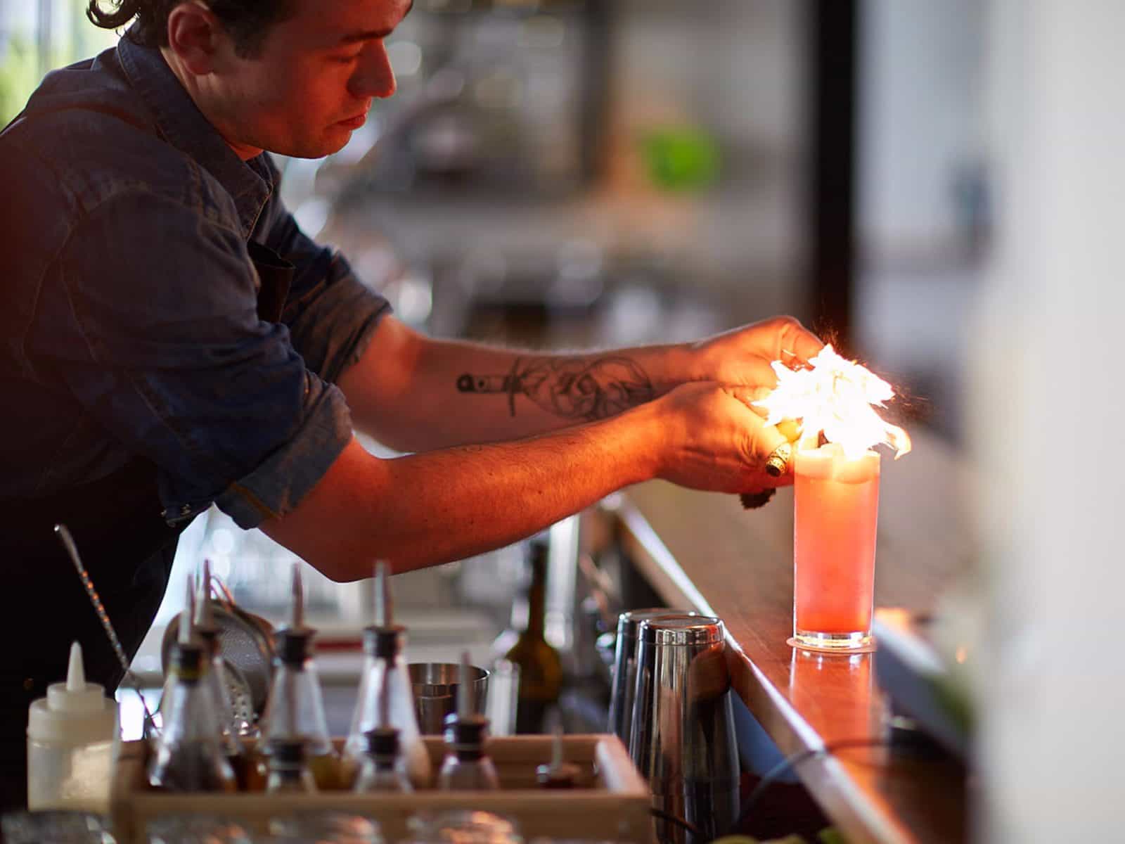 Barman lighting a cocktail on the bar
