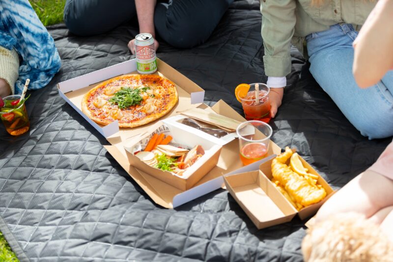 Various food and drinks on a picnic rug