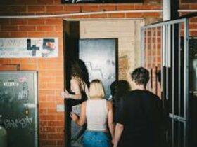 Group of people walking into doorway behind a brick wall